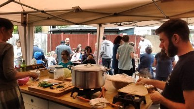 lots of people are milling around an outdoor kitchen where food is being prepared.