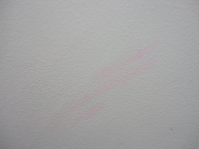 white wall with very faint pink smudge where writing may have been removed