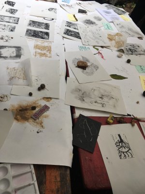 a table scattered with drawings and lino prints